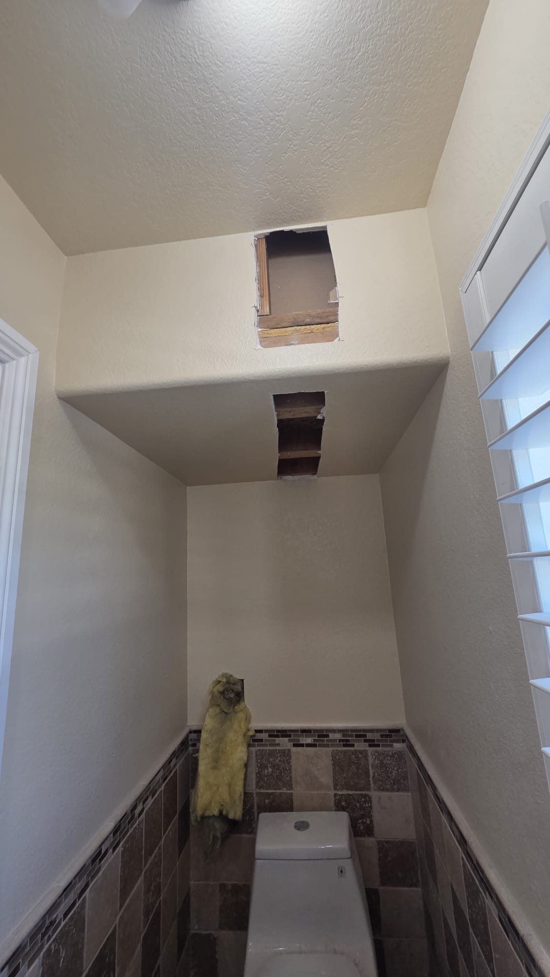 Bathroom wall and ceiling openings above the toilet before drywall repair