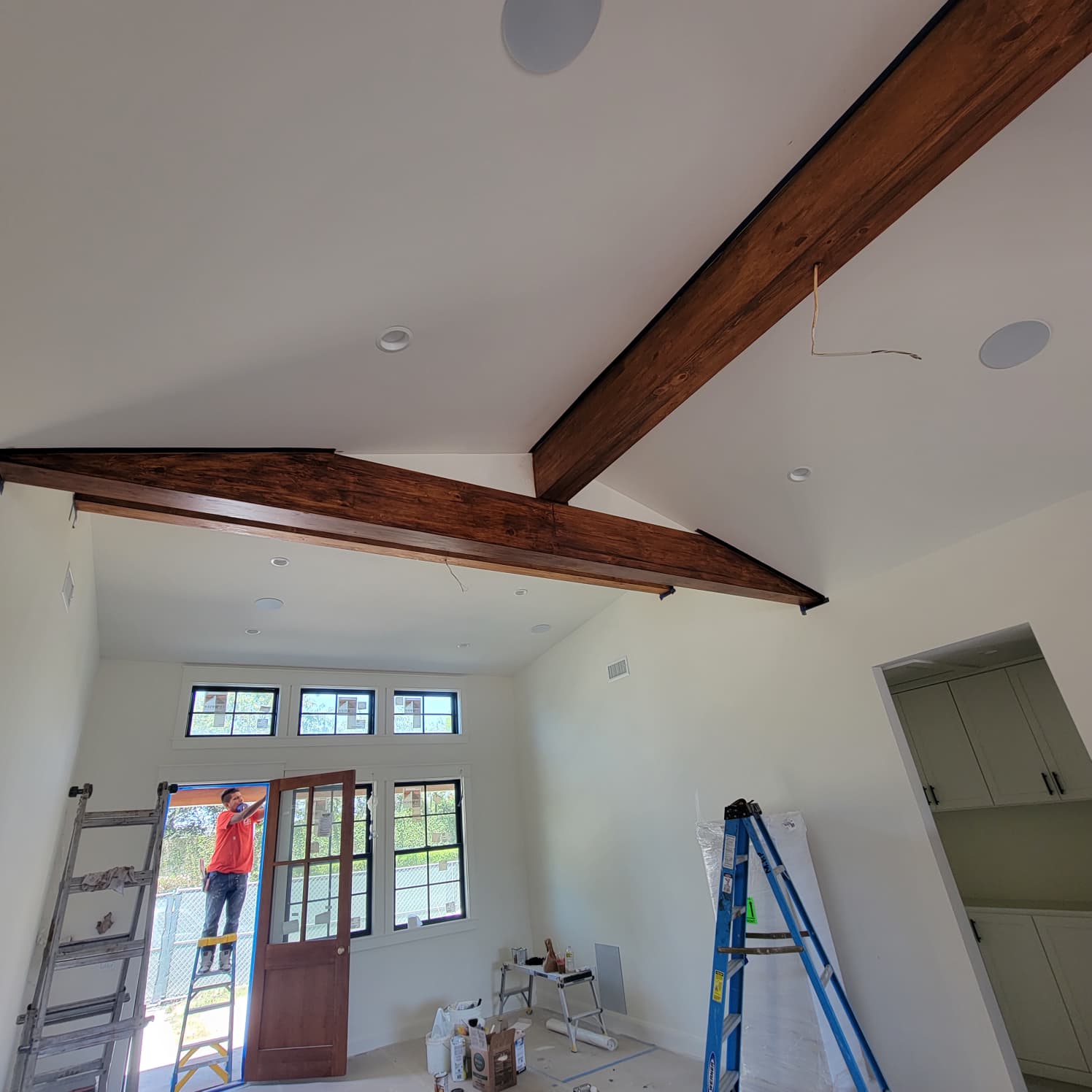 Ceiling beams after staining, showing a rich dark brown wood finish across the vaulted ceiling