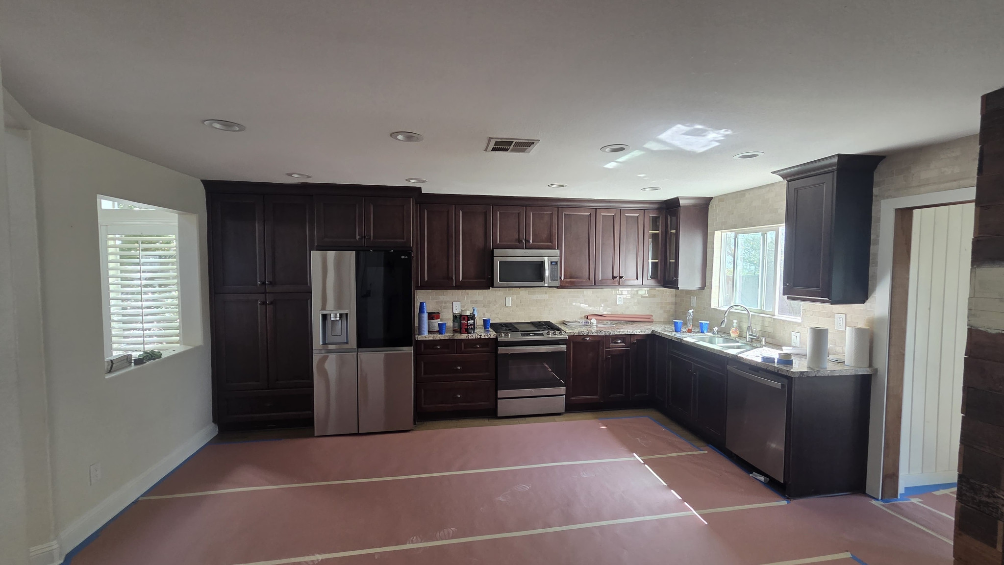 Kitchen after view with dark-brown cabinet doors installed and protective floor covering still in place.