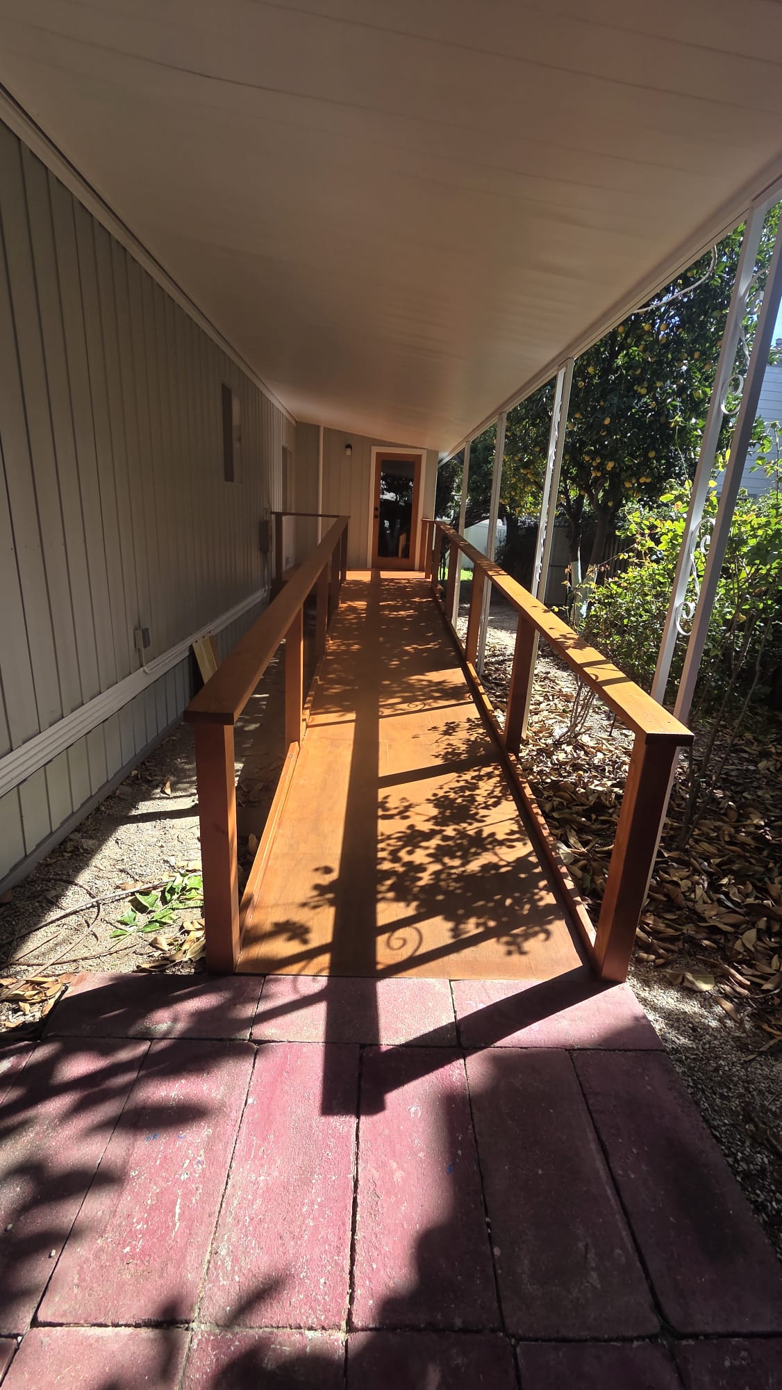 Stained wood walkway and railing along the side of a house