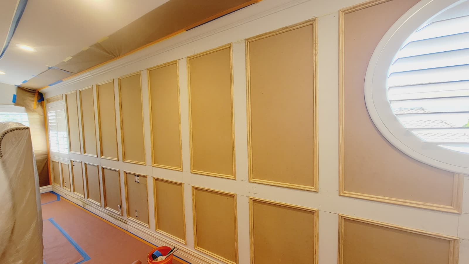Raw decorative wall paneling with unfinished trim and masking tape before painting