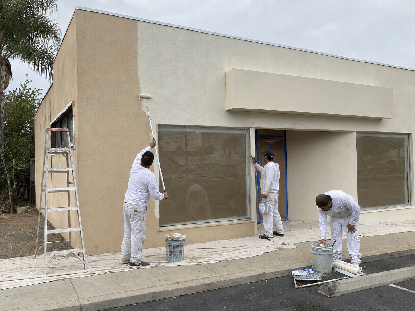 Crew painting the exterior facade of a single-story commercial building