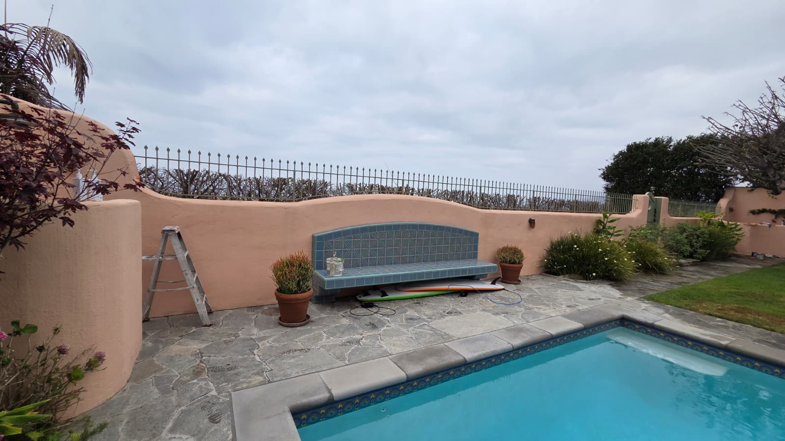 Finished painted exterior garden wall beside a pool and stone patio